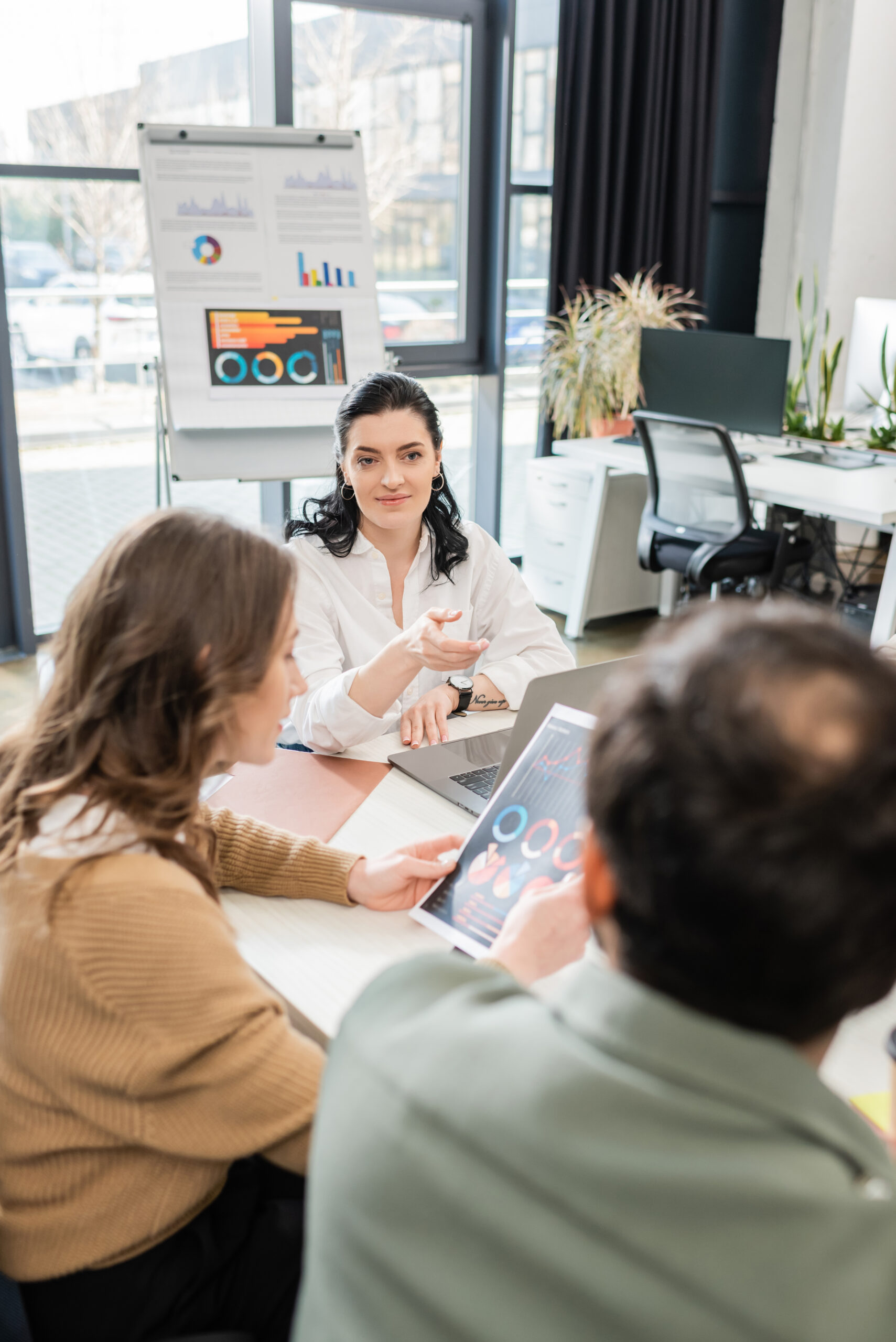 Team leader discussing charts on a tablet with colleagues in a bright office setting